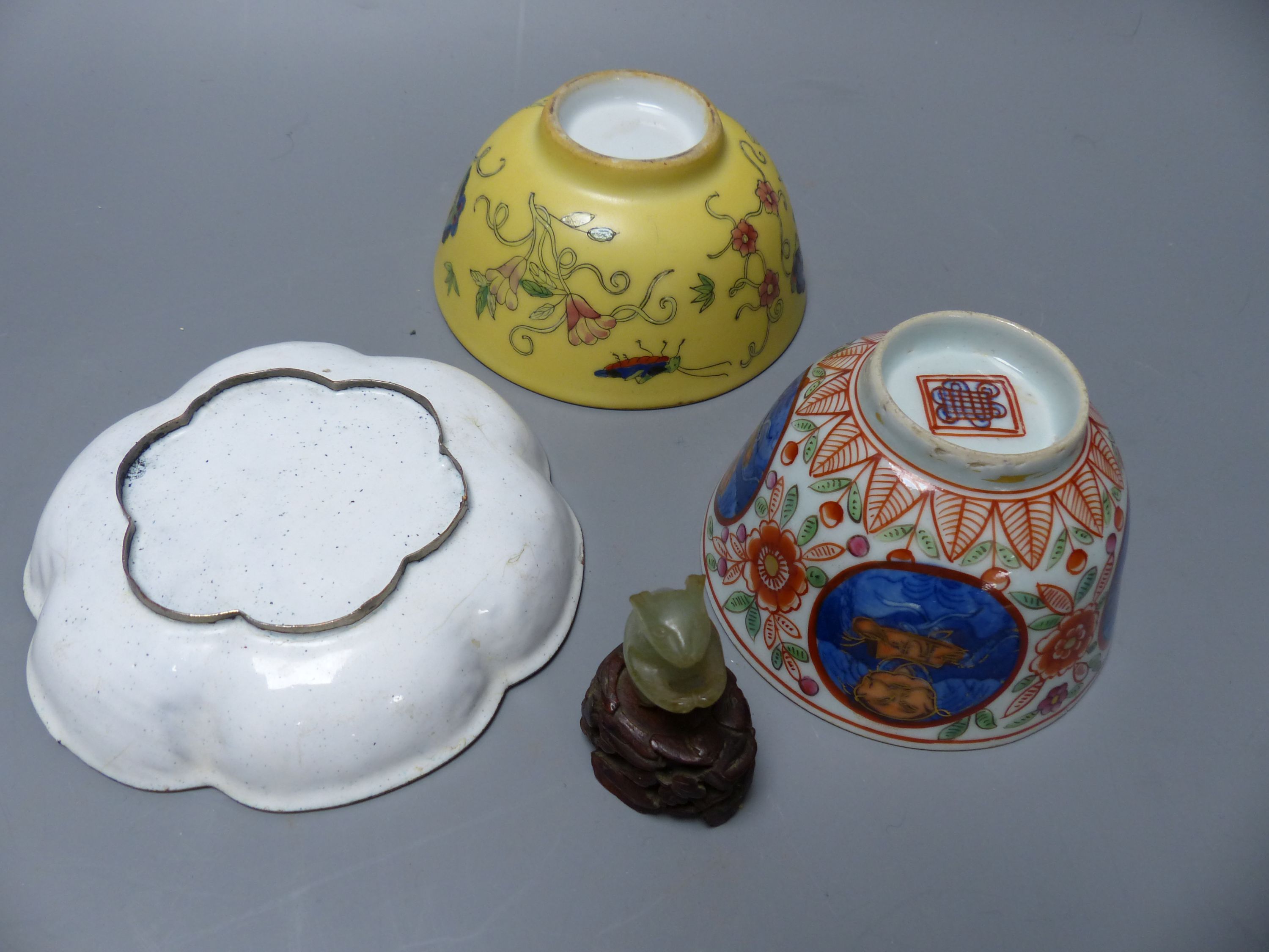 A carved jade mouse on associated hardwood stand, three pieces of Oriental porcelain including an enamel dish and two tea bowls, larges